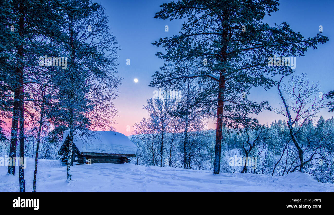 Panoramablick auf die wunderschöne Winterlandschaft Landschaft mit traditionellen Holzmöbeln Tierheim im malerischen Licht am Abend bei Sonnenuntergang in Skandinavien, Norden Euro Stockfoto