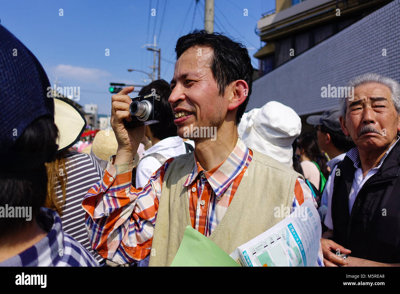 Mann im Publikum lächelte, als er ein Bild auf einem hellen Tag in Japan einrastet. Stockfoto