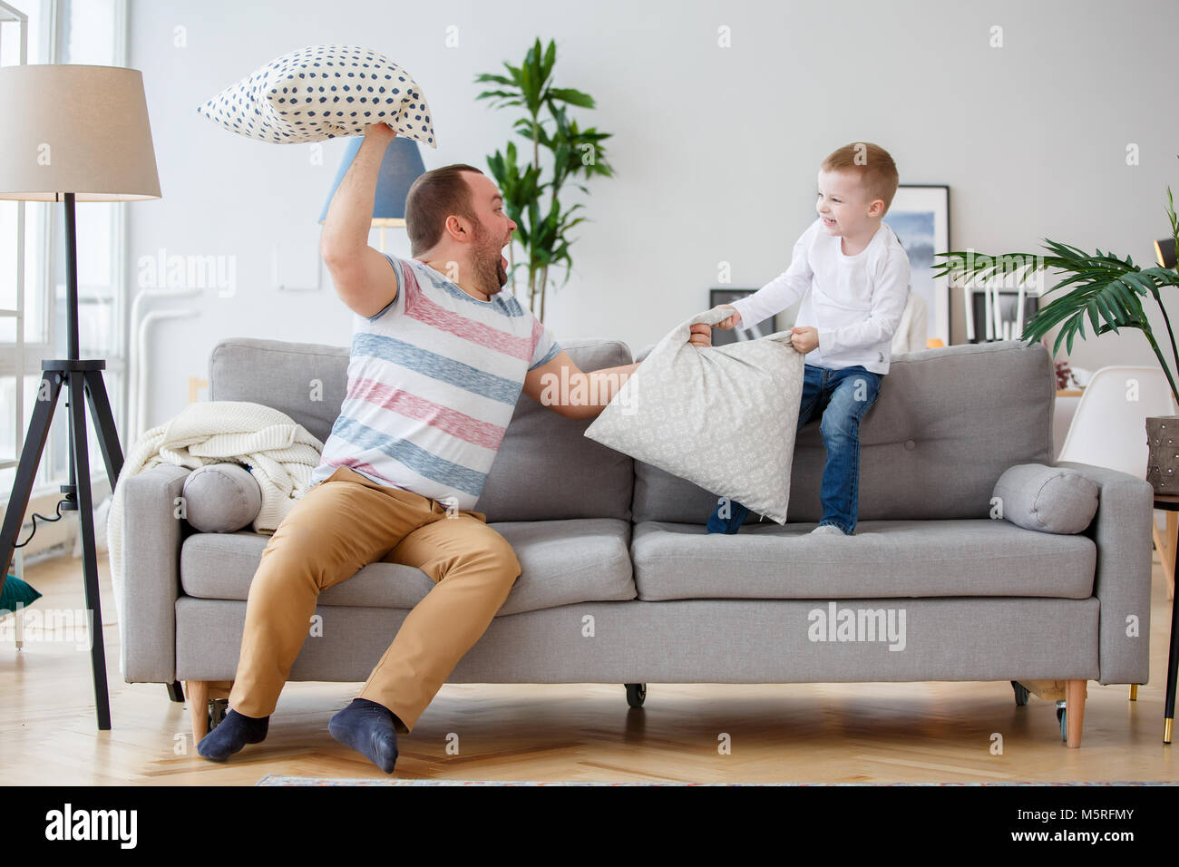 Foto von Vater kämpfen mit Sohn Kissen auf graue Sofa Stockfoto