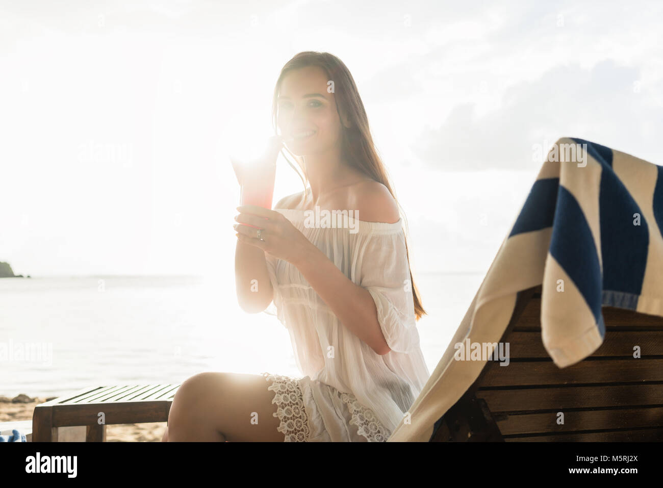 Porträt einer schönen jungen Frau lächelnd, während Sie einen Cocktail Stockfoto