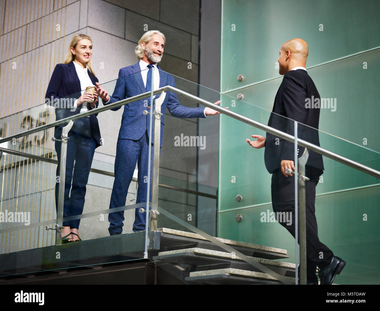Senior Corporate Executive begrüßen Besucher auf der Treppe der modernen Bürogebäude, Low Angle View. Stockfoto