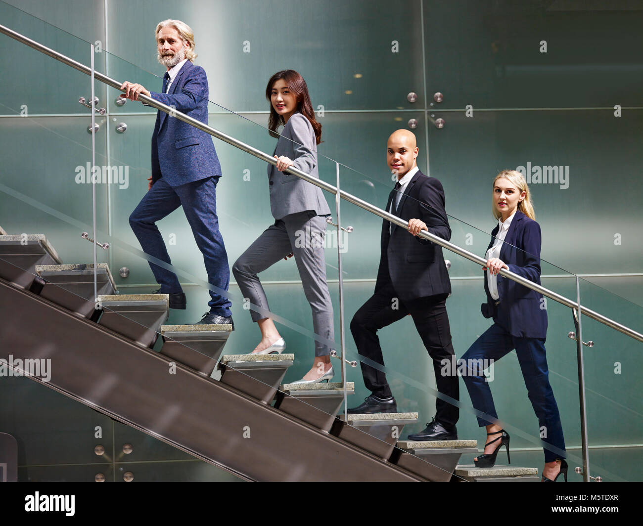 Multinationalen und multiethnischen corporate business Leute aufgereiht auf Treppen der modernen Bürogebäude an der Kamera schaut lächelnd. Stockfoto