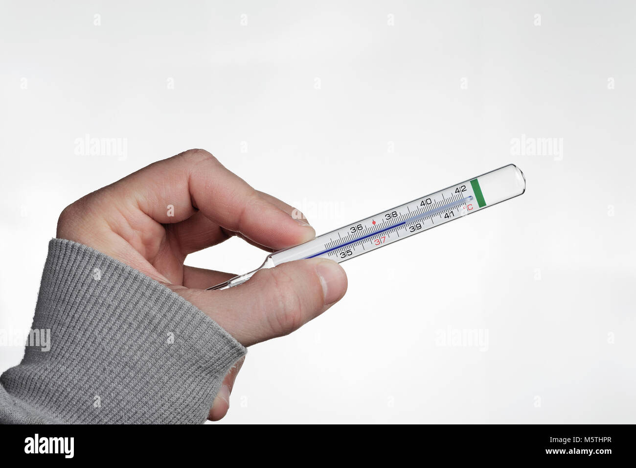 Eine Hand mit einem medizinischen Thermometer zeigt eine hohe Temperatur. Stockfoto