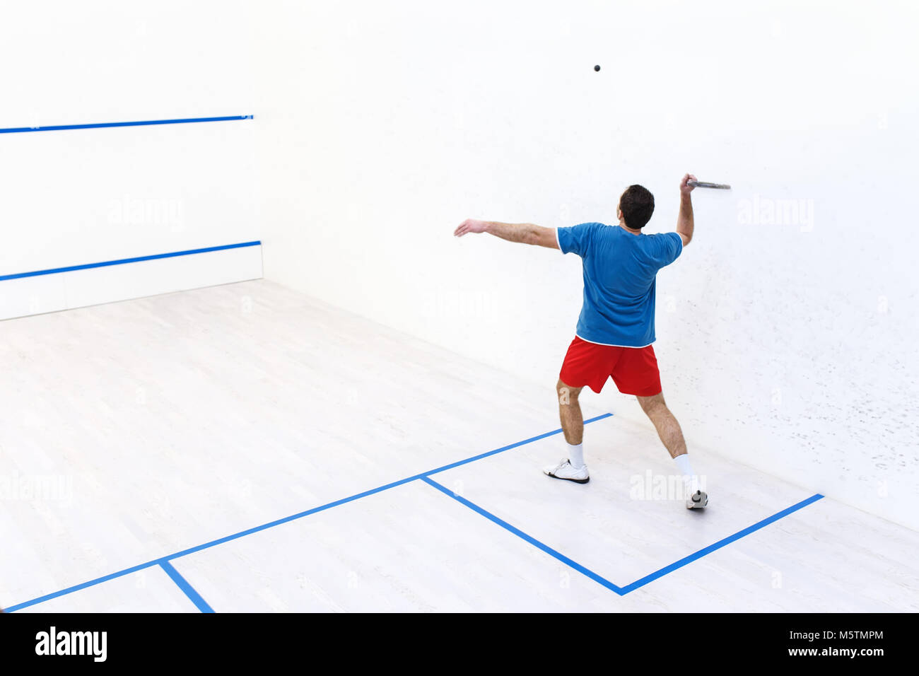 Rückansicht des Squash Spieler Schlagen einer Kugel in einem Squashplatz. Squash Player in Aktion. Mann spielt die Übereinstimmung von Squash. Kopieren Sie Platz. Sport, Menschen, recreat Stockfoto