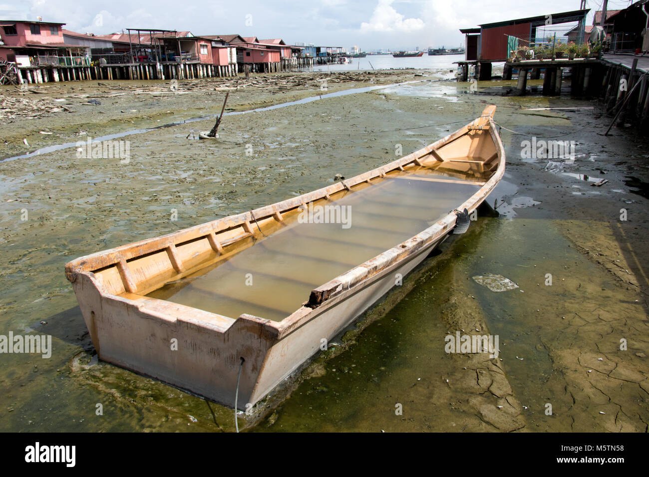 Überflutete Schiff im Schlamm im Village auf Säulen. Verlassene Boot an Clan Stege George Town, Penang, Malaysia. Stockfoto