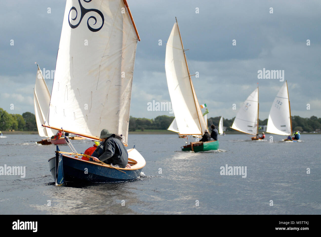 Eine Flotte von Segelschiffen Wettlauf um Tarmonbarry am Fluss Shannon in Irland. Schottische designer Iain Oughtred Helms das nächste Boot. Stockfoto