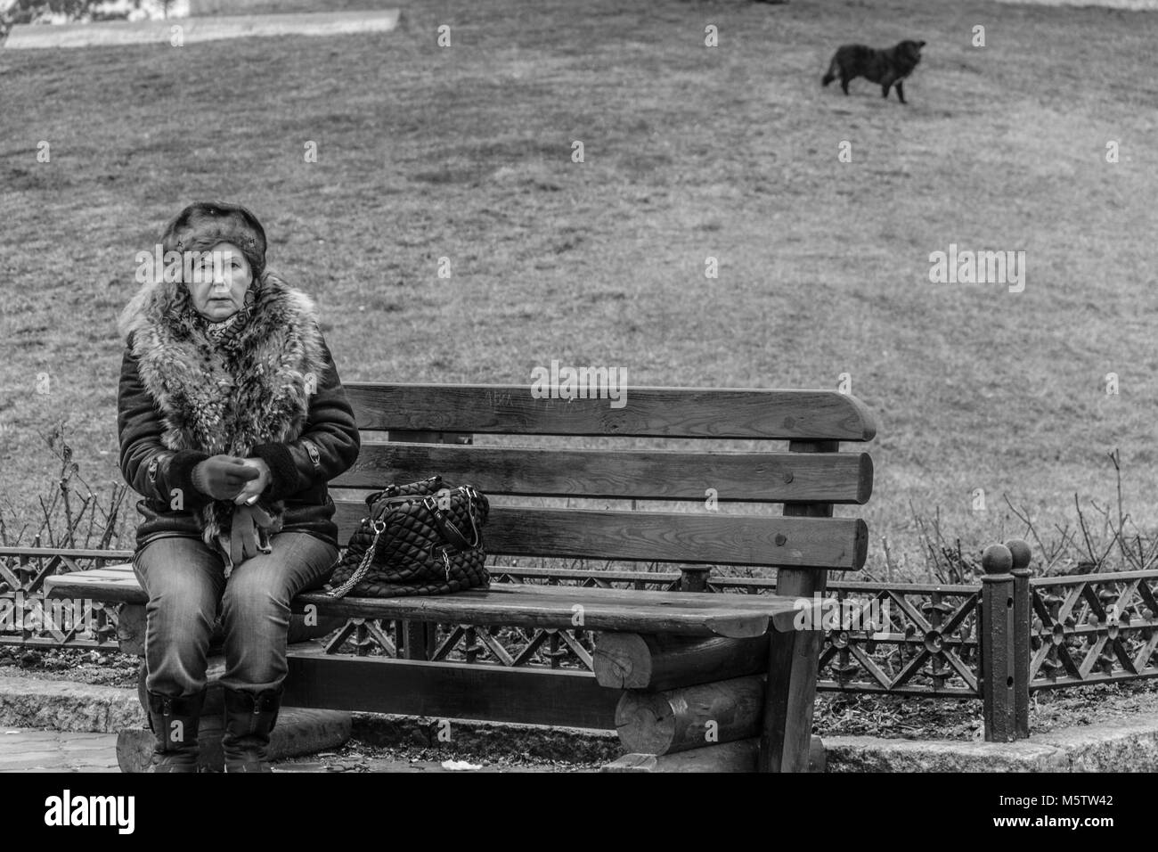 Einsame ältere Frau auf einer Bank im Park, Schwarze und Weiße reportage Foto Stockfoto