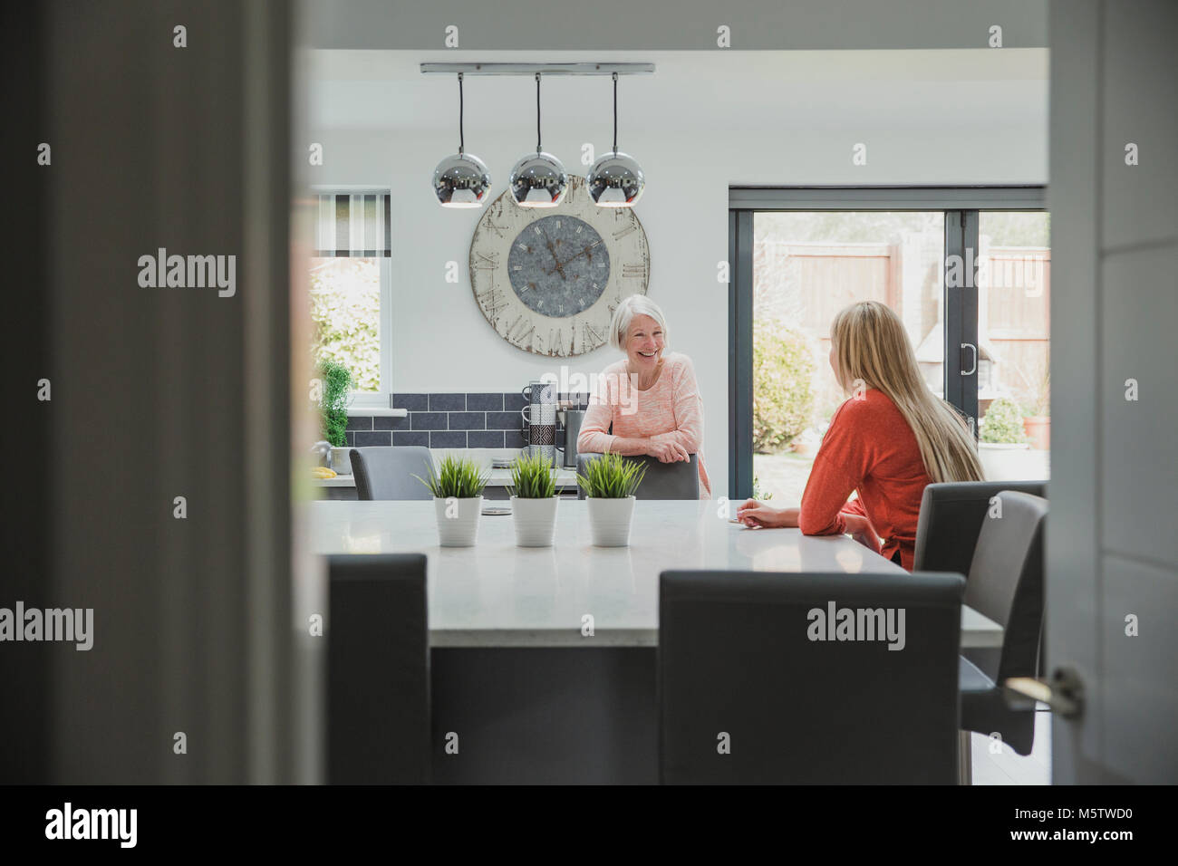 Ältere Frau genießt ein Aufholen mit ihrer Tochter. Sie sind in der Küche ihrer Heimat. Stockfoto