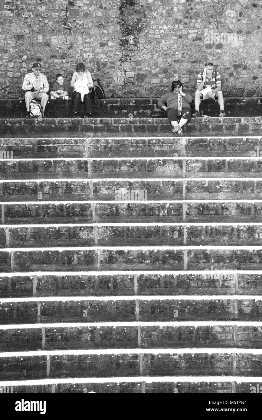 Monochromes Bild von Touristen auf den Stufen des Großen Theater in Pompeji, Italien sitzen. Stockfoto