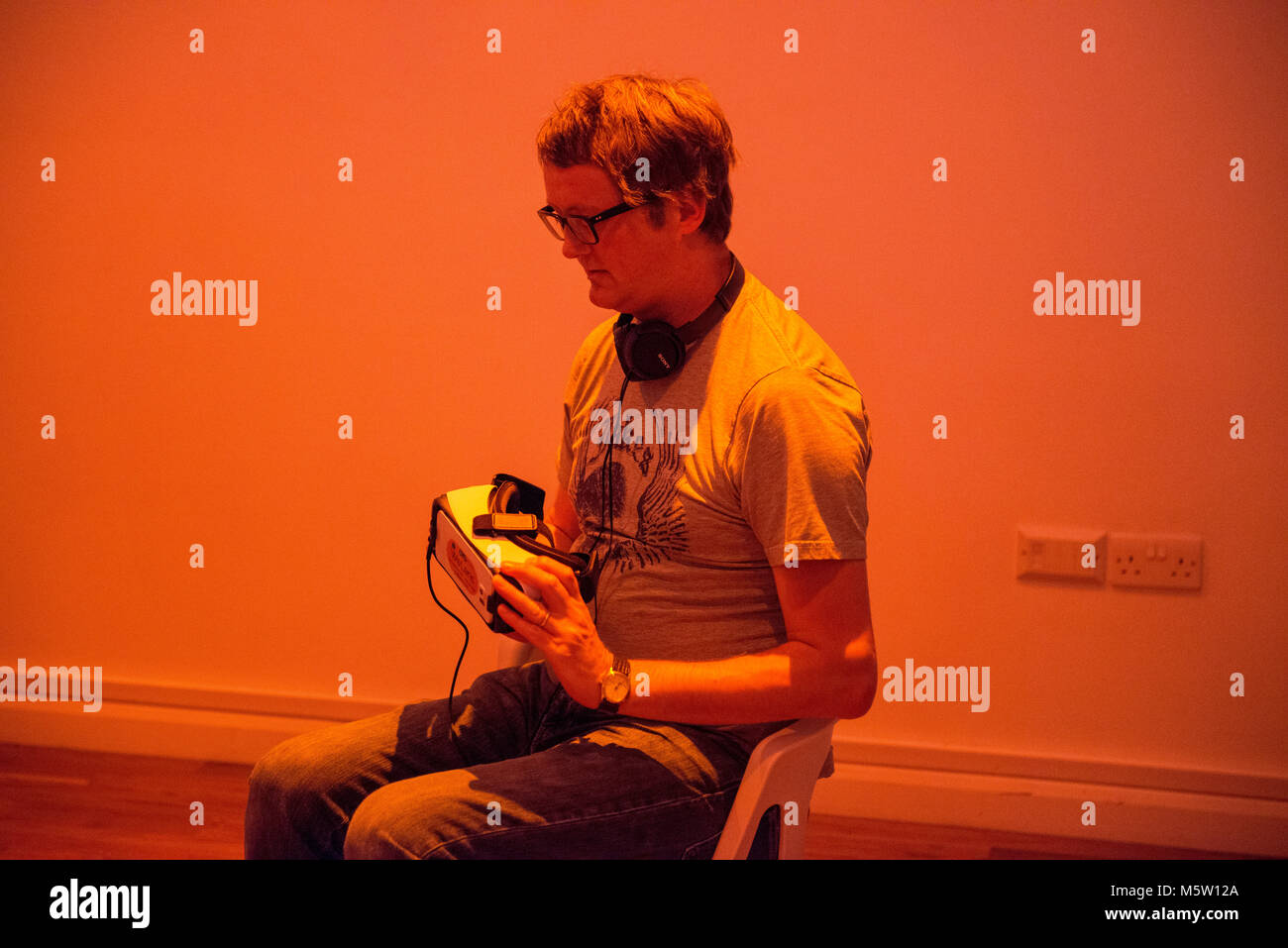 Echte Menschen verwenden, um eine interaktive Virtual Reality Headset und Kopfhörer in einer Kunstgalerie Stockfoto