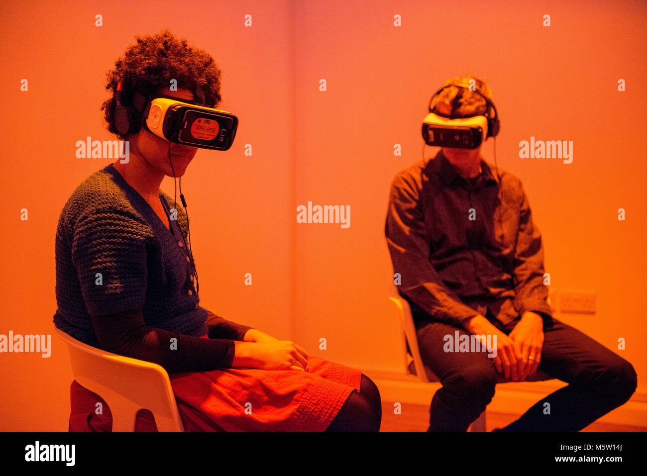 Echte Menschen verwenden, um eine interaktive Virtual Reality Headset und Kopfhörer in einer Kunstgalerie Stockfoto