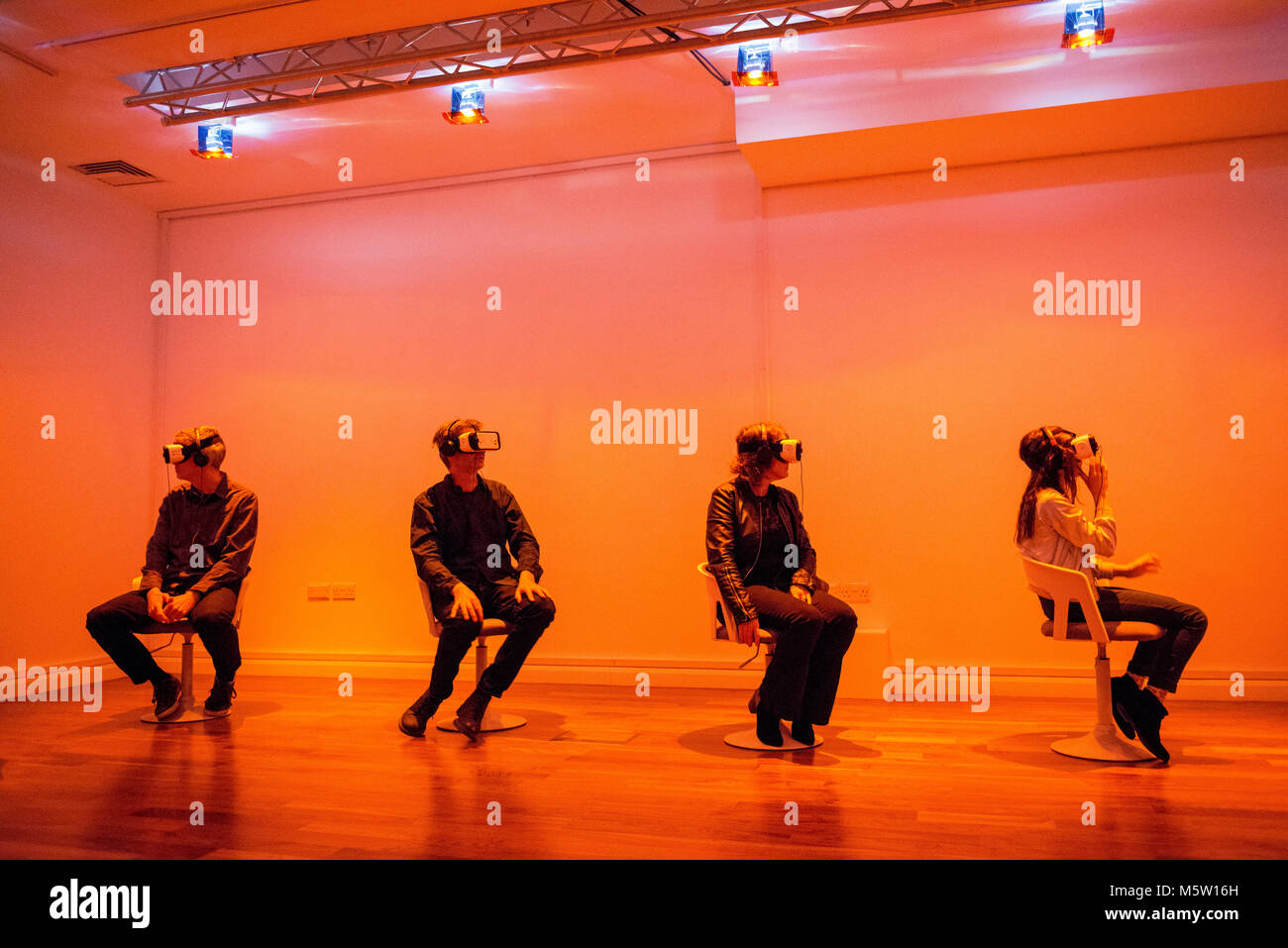 Echte Menschen verwenden, um eine interaktive Virtual Reality Headset und Kopfhörer in einer Kunstgalerie Stockfoto