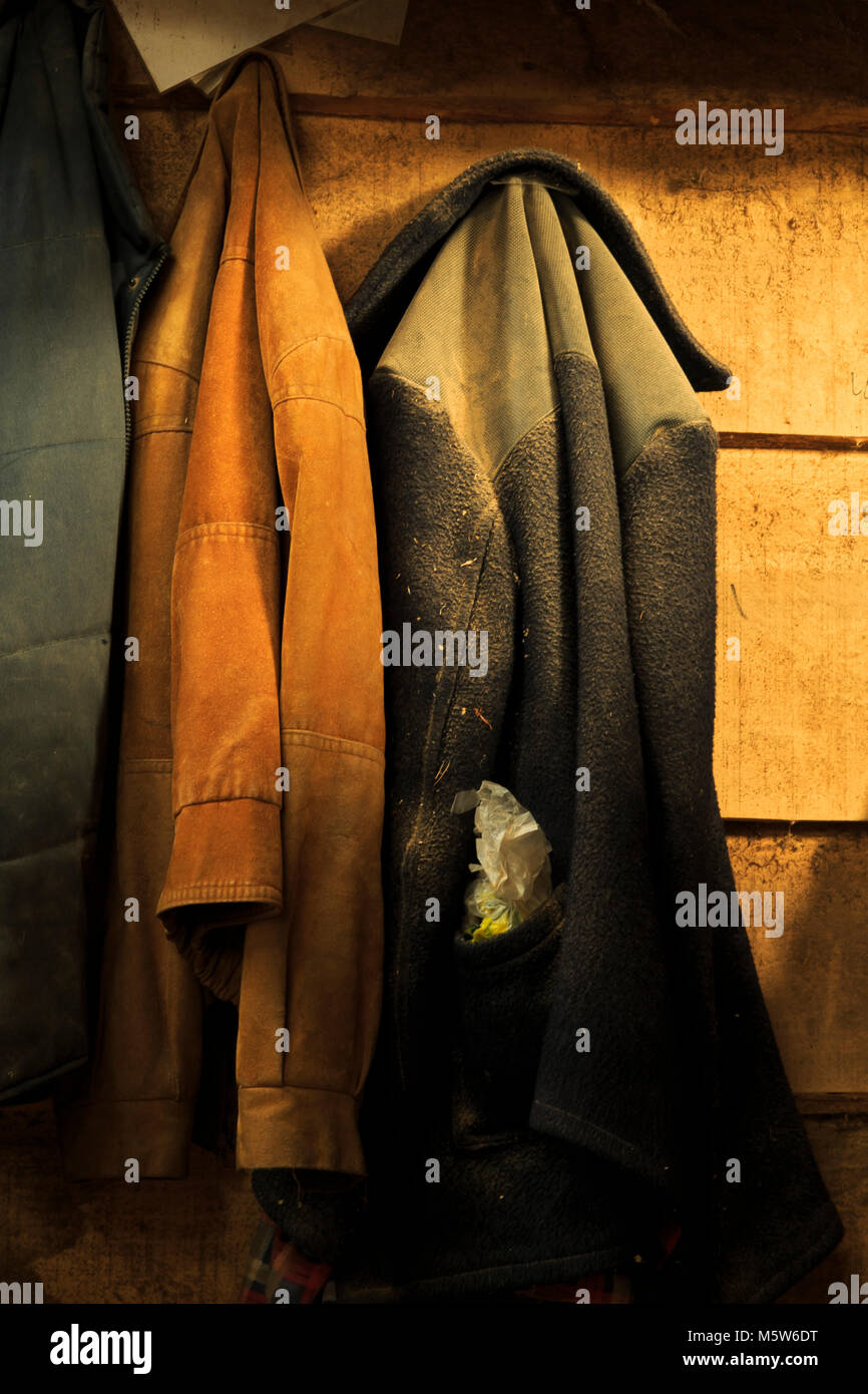 Der alte Arbeiter Jacken aufhängen auf heringe in einer alten, staubigen Werkstatt. Stockfoto
