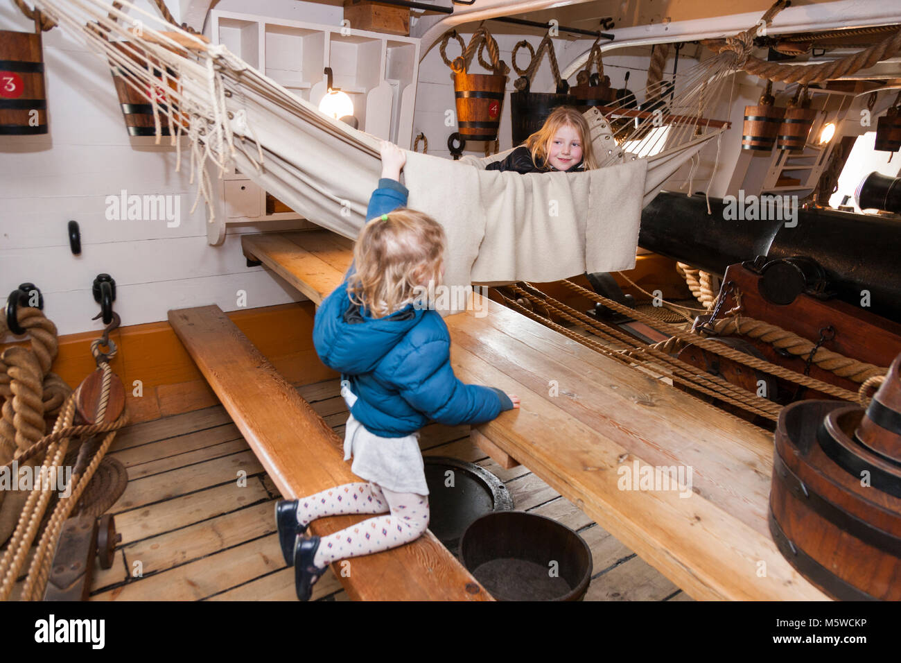 Touristische spielen die Kinder auf Hängematte aufgehängt zwischen 68 Pounder Beförderung Gewehren auf die HMS Warrior, Portsmouth Historic Dockyard/historischen Werften. UK. (95) Stockfoto