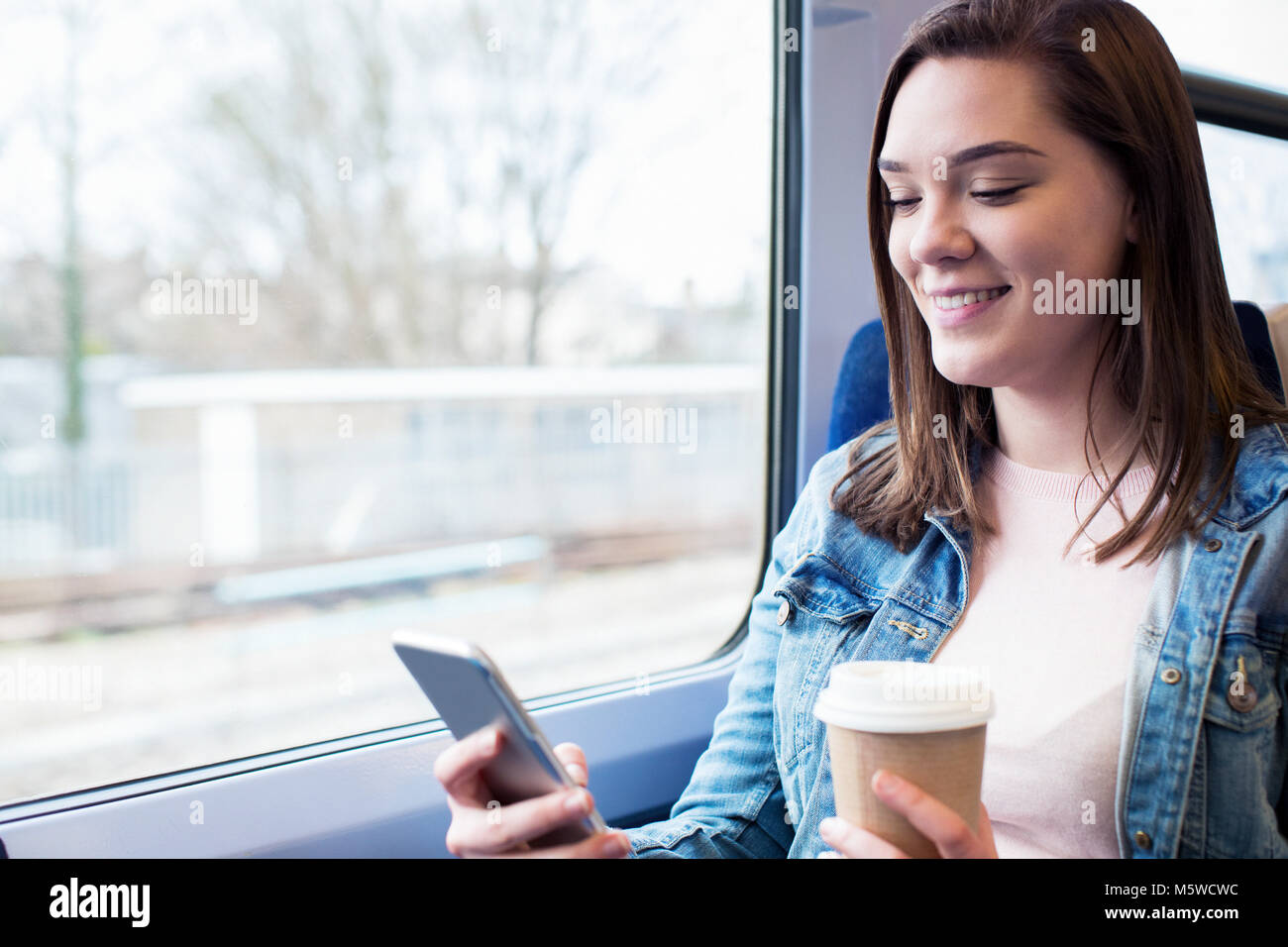 Junge Frau SMS auf Handy während der Fahrt Stockfoto