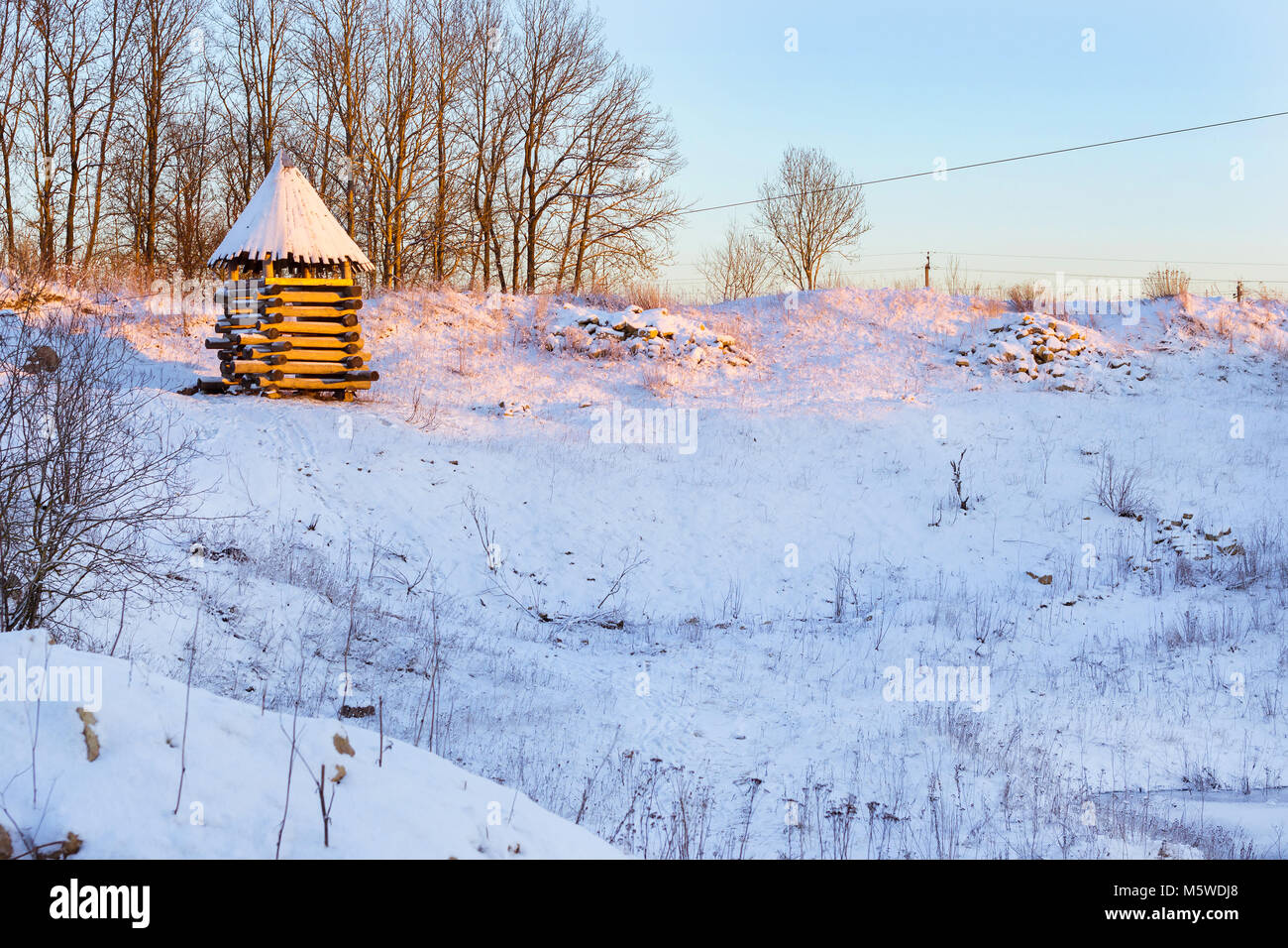 Hölzerne Aussichtsturm steht auf einem schneebedeckten Berg. Winterlandschaft bei Sonnenuntergang. Dekorationen der alten russischen Befestigungsanlagen in den lustigen Nicholas Festung Stockfoto