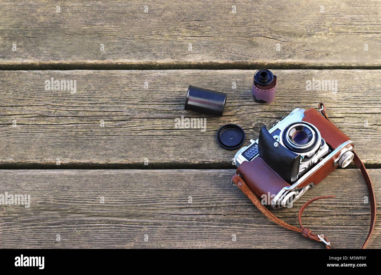 Alten retro Kamera in eine braune Ledertasche und einem fotografischen Film Roll auf verdorrte Holzplanken, Vintage Style Stockfoto