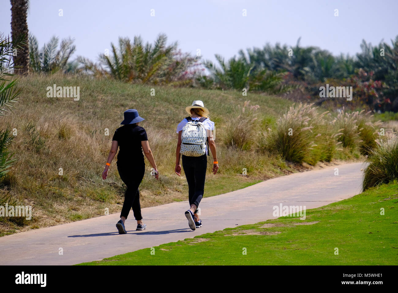 Zwei junge Frauen, die zu Fuß auf Joggingpfad auf Saadiyat Island Golf Course, Abu Dhabi Stockfoto