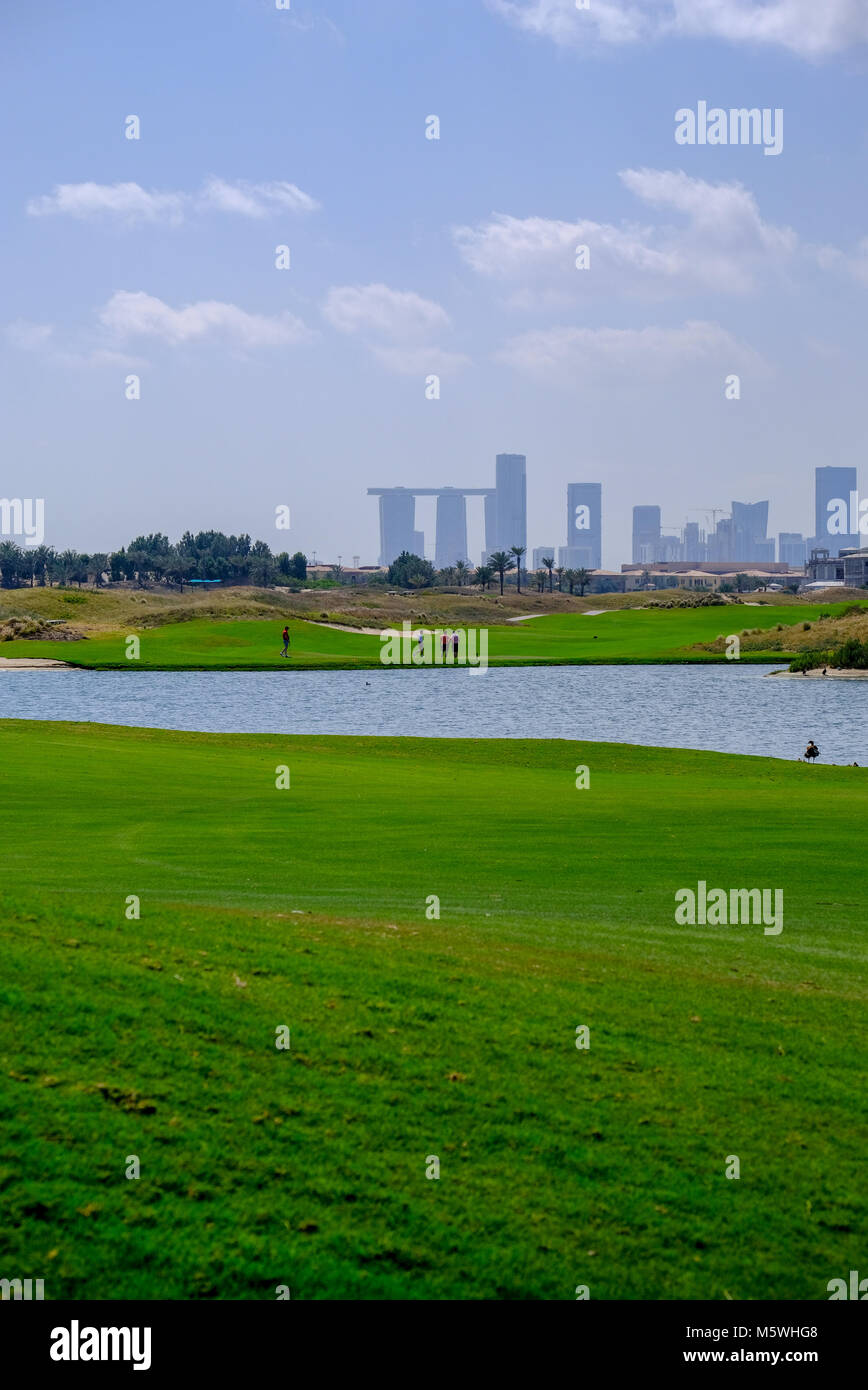 Grünes Feld von Saadiyat Island Golf Course mit städtischen Gebäude in einem Abstand. Stockfoto