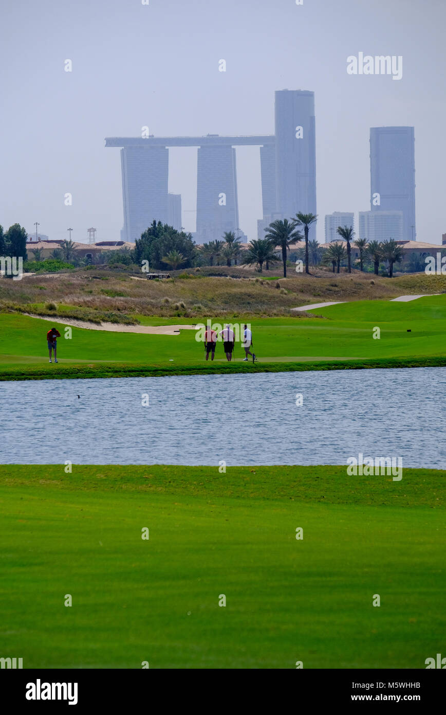 Grünes Feld von Saadiyat Island Golf Course mit städtischen Gebäude in einem Abstand. Stockfoto