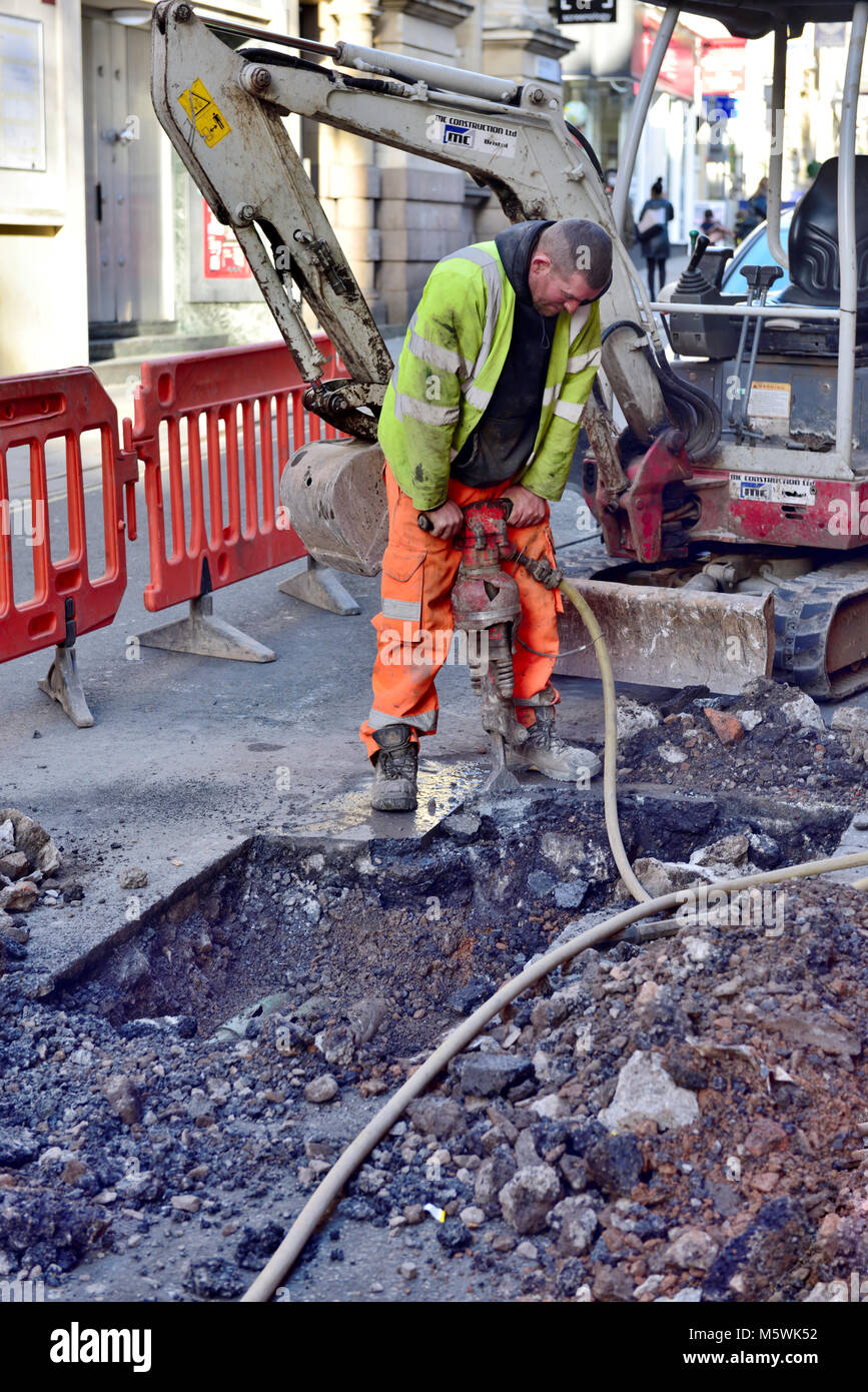 Arbeiter graben Loch in Straße mit abbruchhammer bis an die Oberfläche durchbrechen, Großbritannien Stockfoto