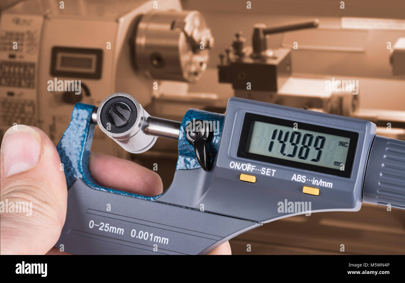 Detail der Hand Facharbeiter mit digitalen Mikrometerschraube messen. Die genaue Messung der lineare Lager durch Messen Werkzeug- und Drehmaschine im Hintergrund. Stockfoto
