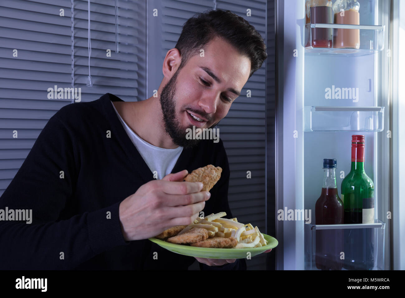 Nahaufnahme einer Lächelnden jungen Mann essen gebratene Nahrung in der Platte Stockfoto