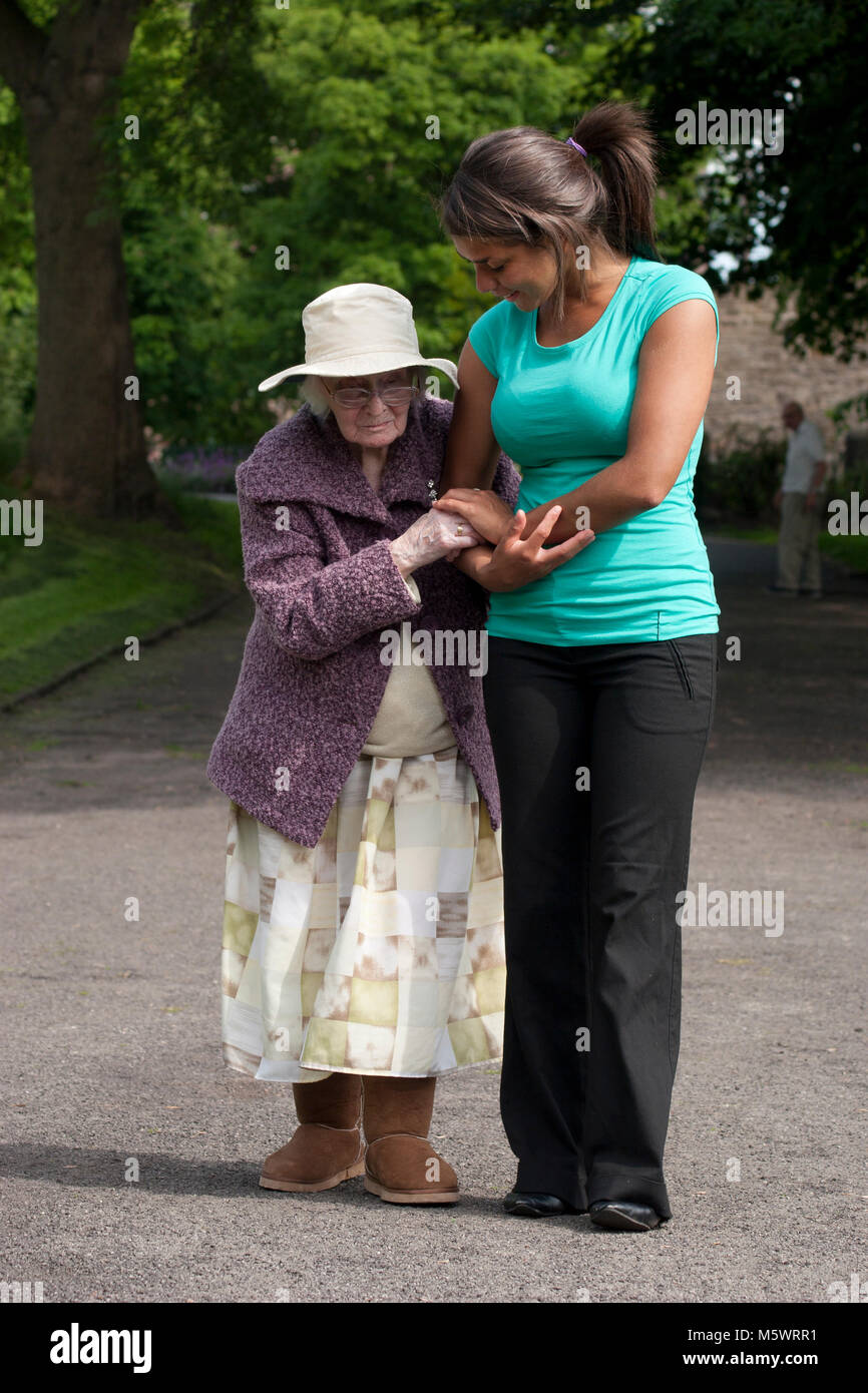 Multikulturelle junge Frau Pfleger mit geriatrischen Dame im Park Stockfoto