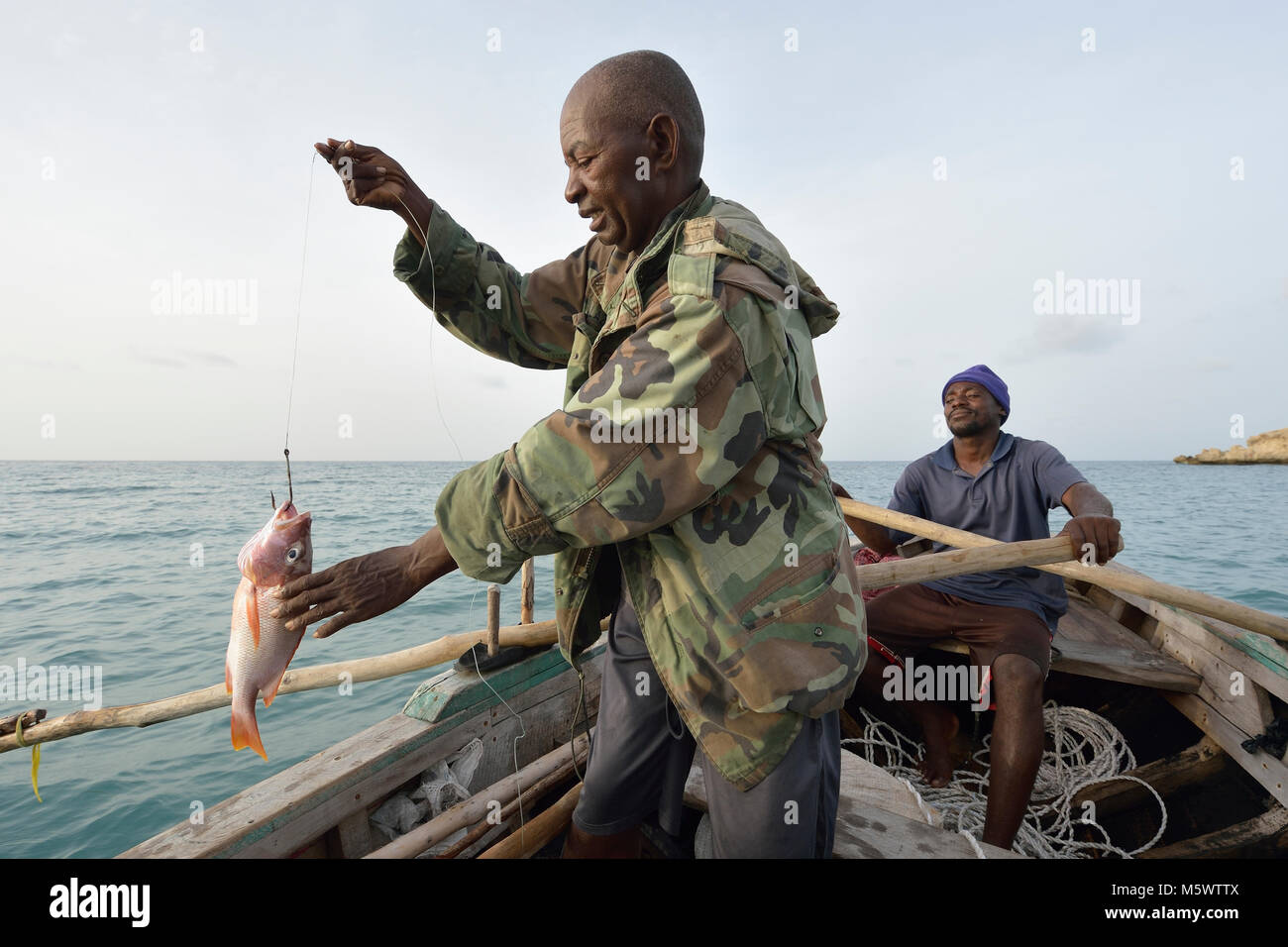 Ein Jahr nach dem Hurrikan Matthew verwüstet Teile von Haiti, Marcilien Georges zieht in ein Fisch in einem kleinen Fischerboot vor der Küste des nordwestlichen Haiti. Stockfoto