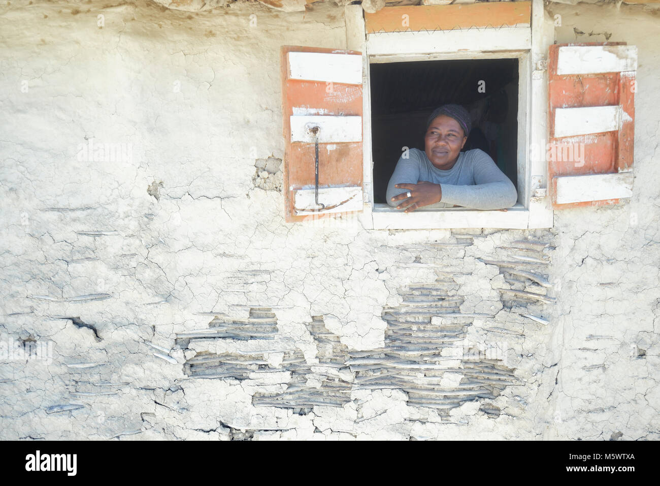 Michel Louis Marie schaut aus dem Fenster eines Hauses in der haitianischen Gemeinschaft von Ganthier. Stockfoto