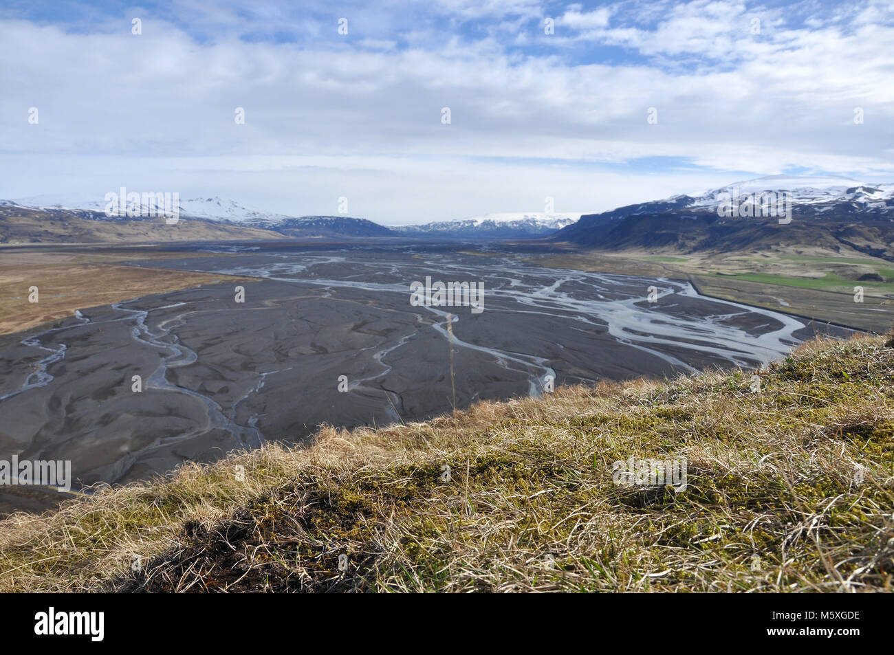 Blick über die isländische Hochwasserebene von der Spitze eines Hügels mit Bergen und Gletscherhintergrund. Stockfoto