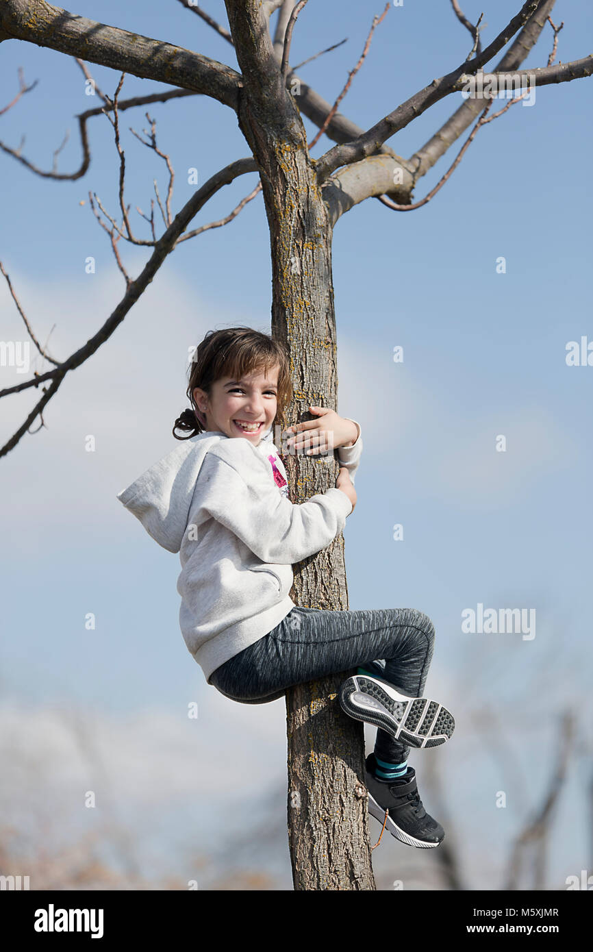10 Jahre alte Mädchen kletterte in einem Baum lächelnd. Horizontale shot mit Tageslicht Stockfoto
