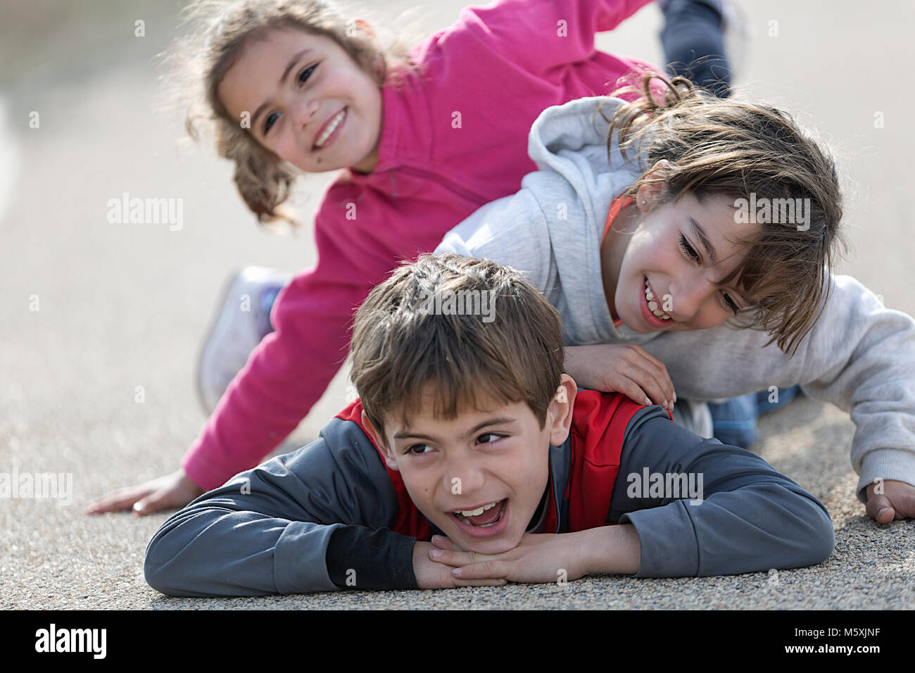 Drei Kinder auf dem Boden liegend eine auf der anderen. Horizontale shot mit Tageslicht Stockfoto