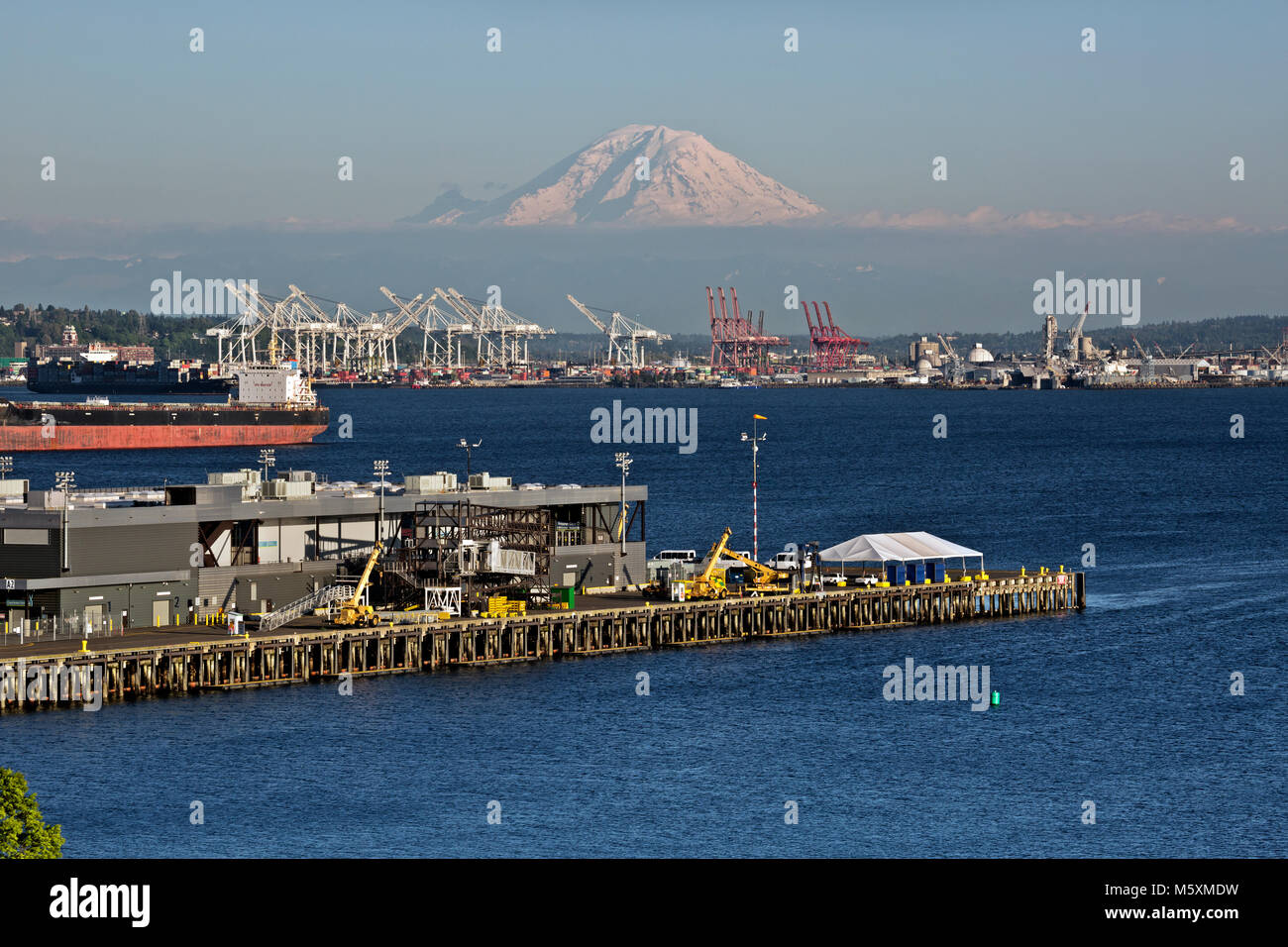 WA13730-00...WASHINGTON - Blick auf Mt. Rainier, Elliott Bay und die Kräne zum Be- und Entladen der Containerschiffe an der Seattle Waterfront. 2017 Stockfoto
