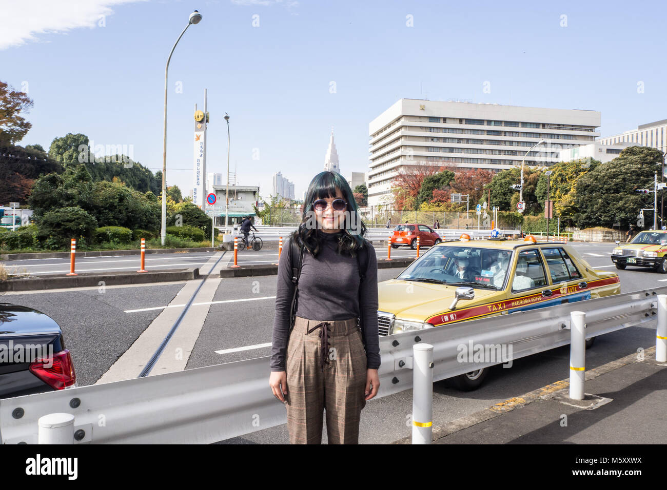 Eine schicke Frau an der berühmten Genko Avenue mit schönen Bäumen, Gelb im Herbst in der Meiji Jingu Gaien Park gedreht haben, posiert Stockfoto