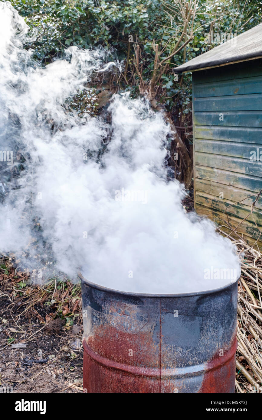 Gartenabfälle verbrennen in Metall im heimischen Garten drum, Gloucestershire England Großbritannien Stockfoto