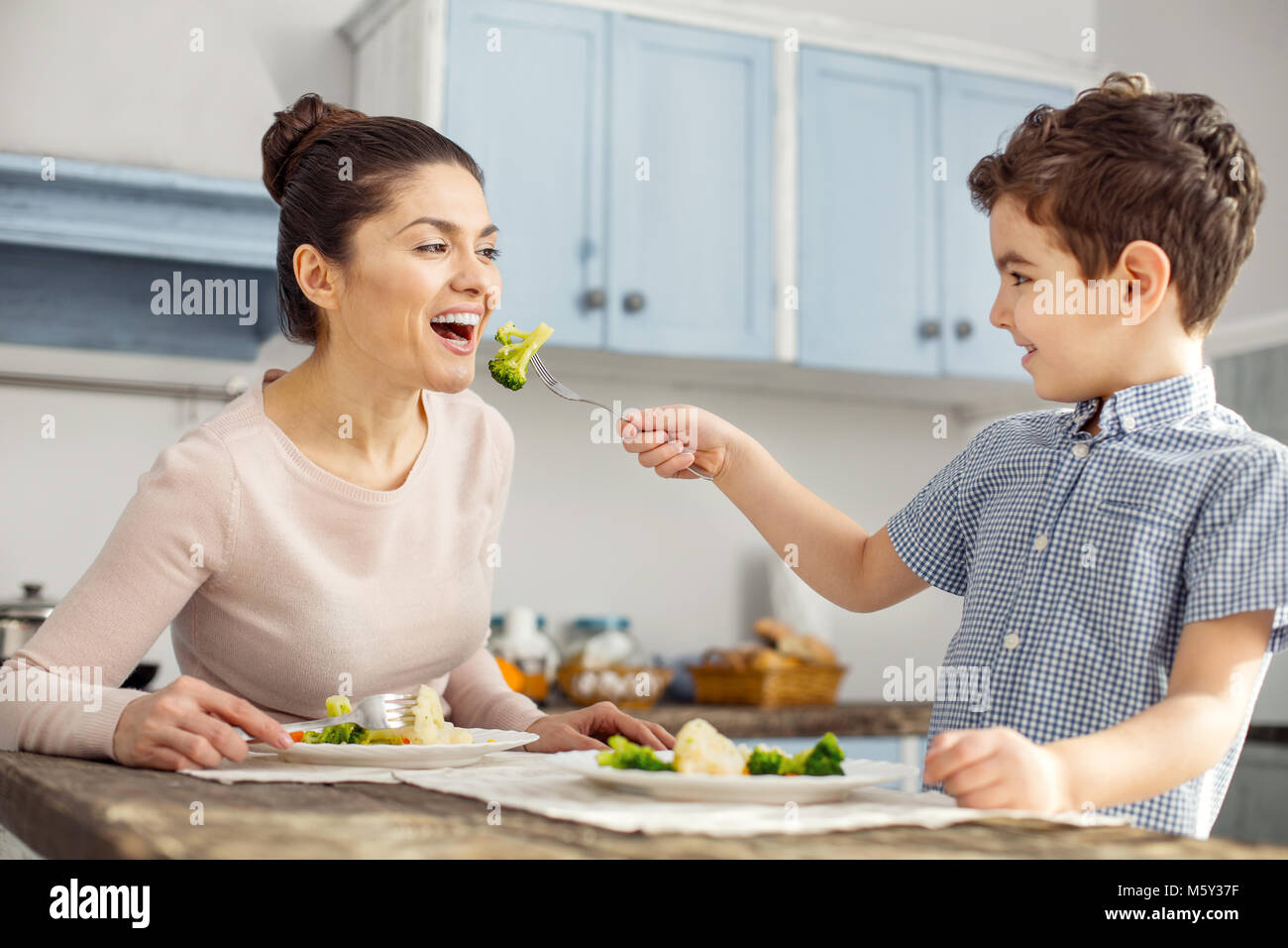 Lächelnde Junge seine Mutter füttern Stockfoto