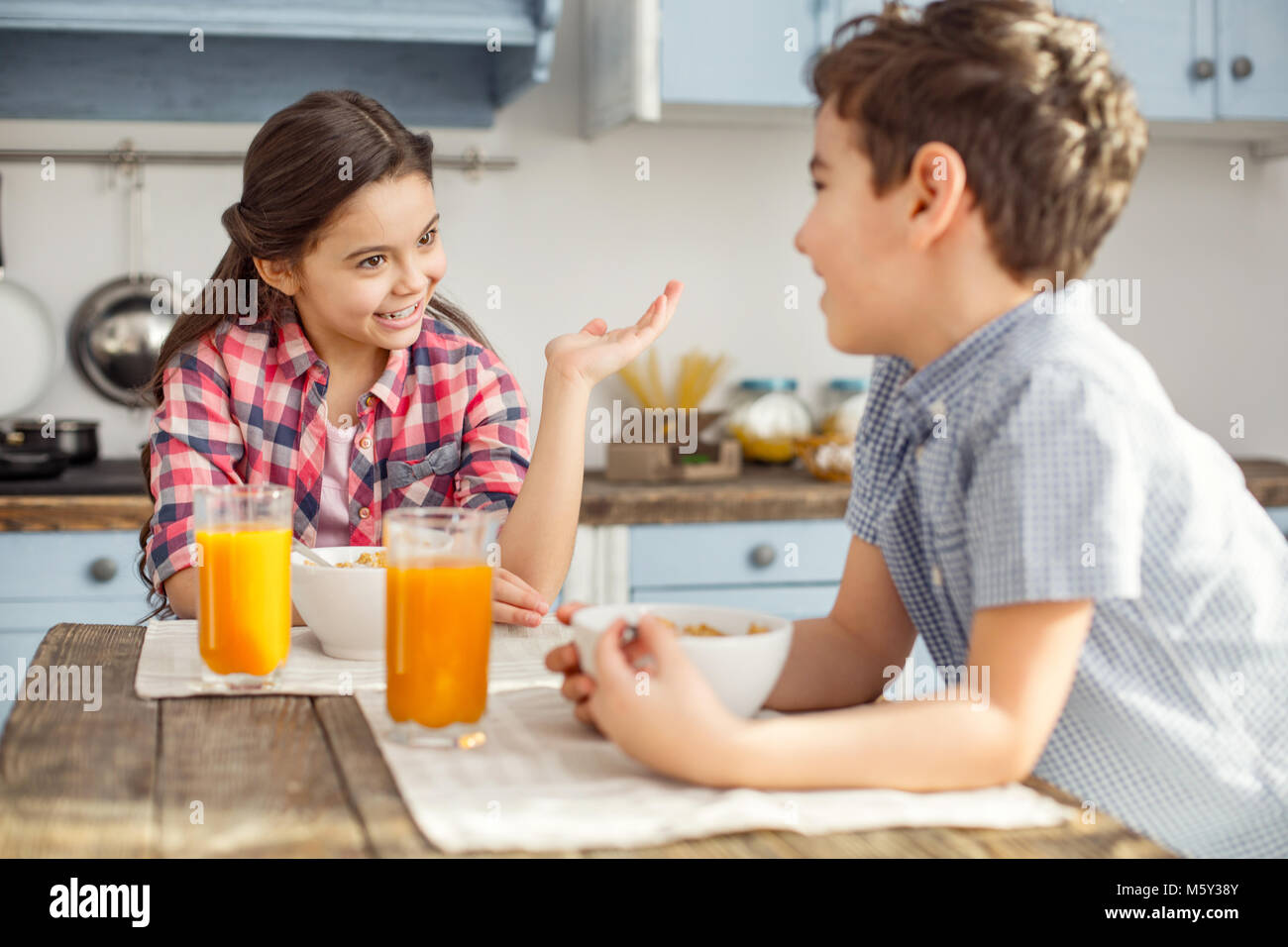 Fröhliches Mädchen reden mit ihrem Bruder beim Frühstück Stockfoto