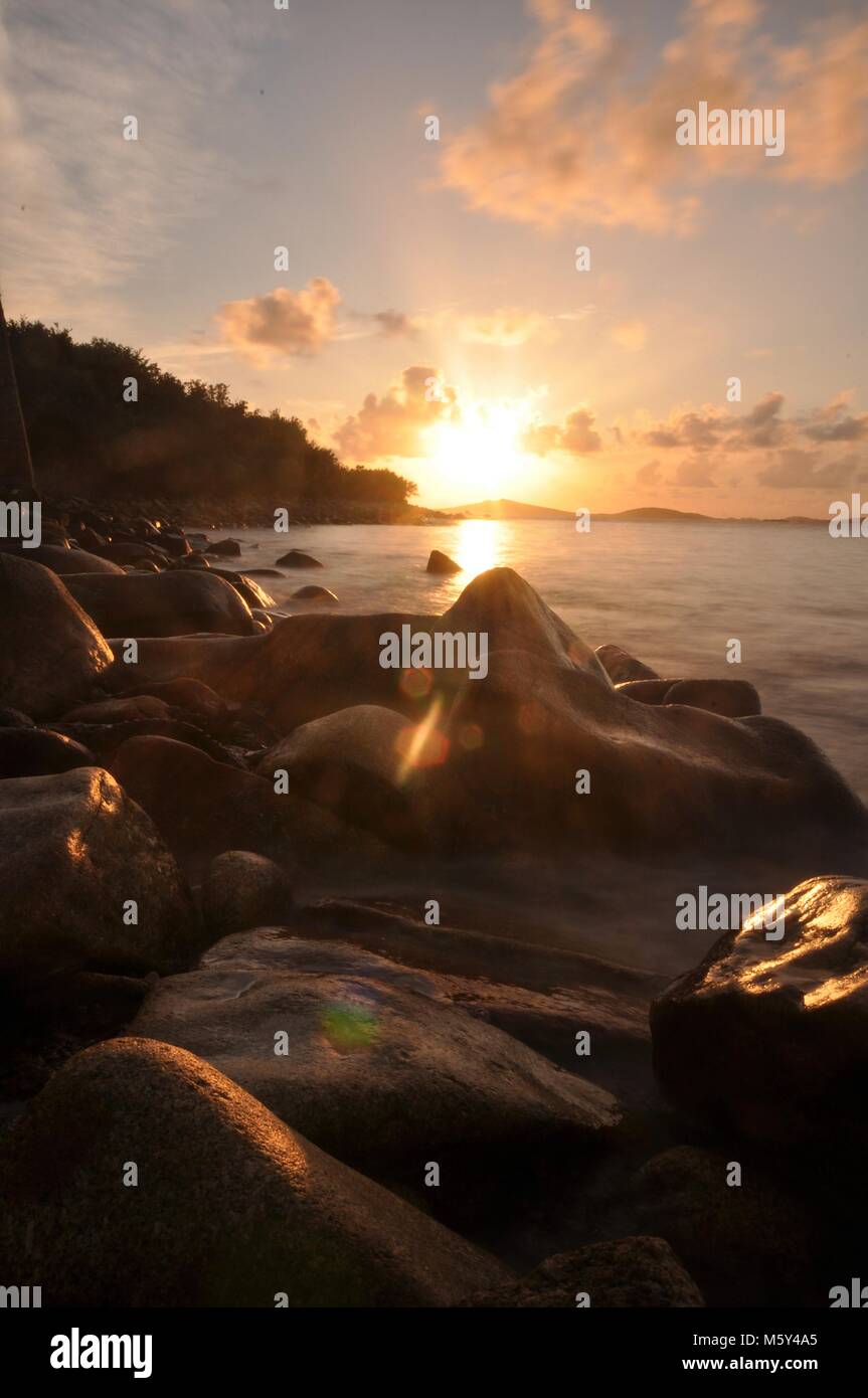 Sonnenuntergangs-Seestücke über felsiger Küste mit langer Belichtung und weichem Wasser. Isles of Scilly, Blick über das Meer zur Insel Samson bei Sonnenuntergang. Stockfoto