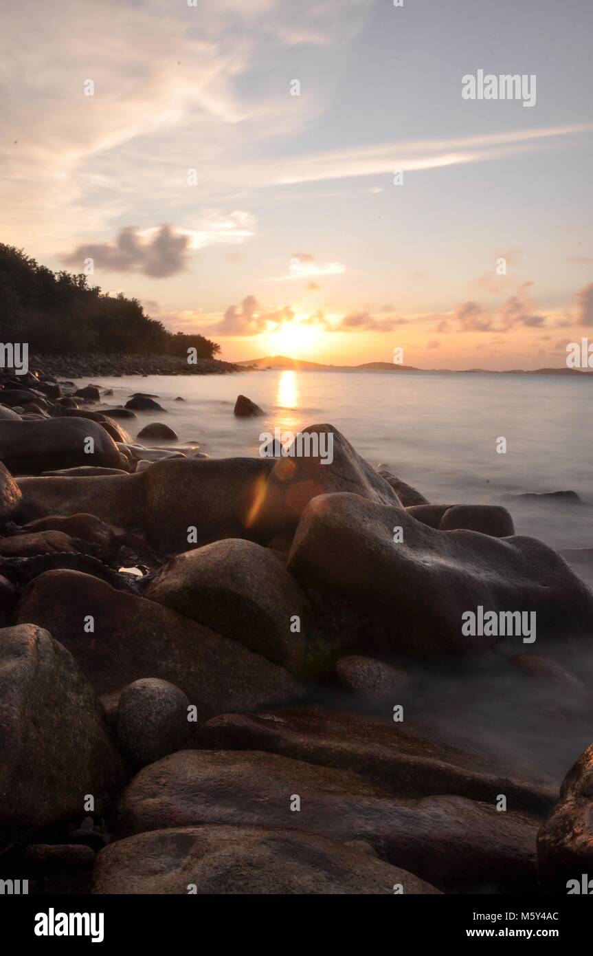 Sonnenuntergangs-Seestücke über felsiger Küste mit langer Belichtung und weichem Wasser. Isles of Scilly, Blick über das Meer zur Insel Samson bei Sonnenuntergang. Stockfoto
