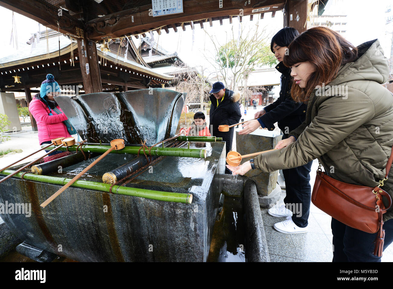 Eine japanische Frau Durchführung temizu Ritus - reinigt Ihre Hände über die bunte Kushida Heiligtum in Hakata, Fukuoka, Japan. Stockfoto