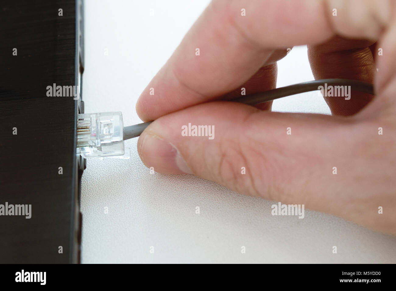 Die menschliche Hand in einem LAN-Kabel stecken an den persönlichen Laptop Computer, selektiver Fokus Stockfoto