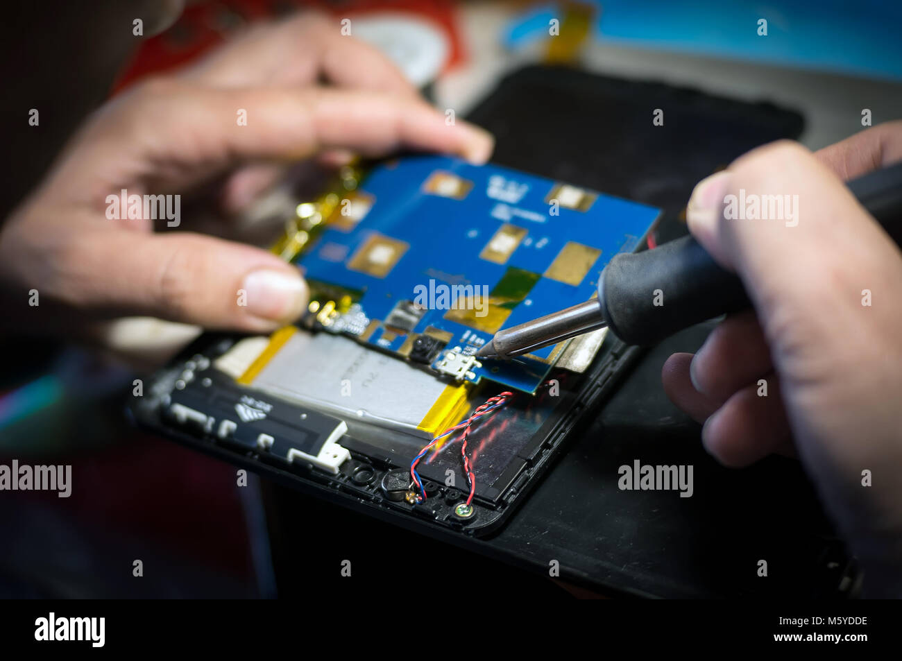 Hände halten einen Lötkolben, close-up. Handy Reparatur und Tablet Stockfoto