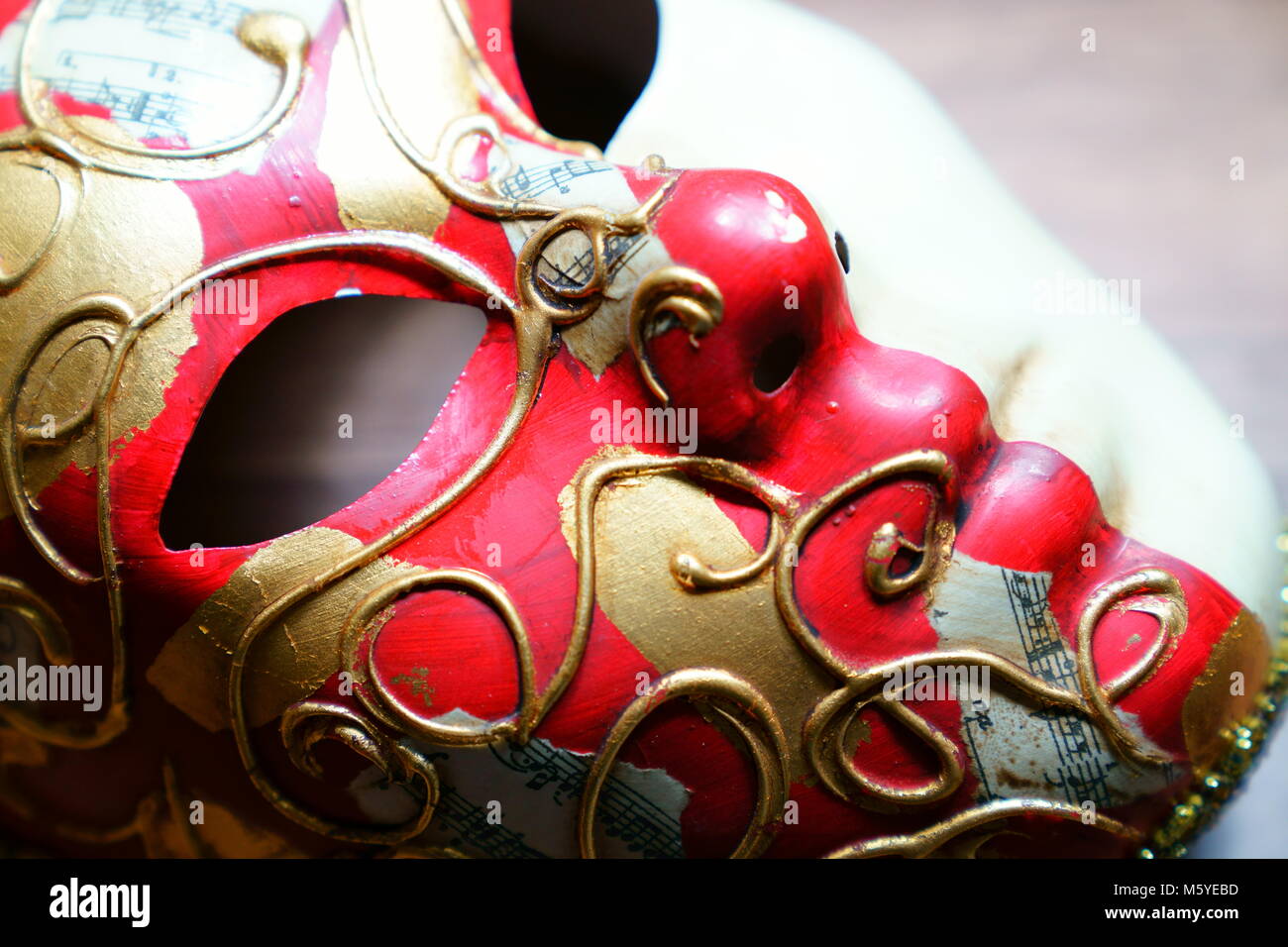 Musik Hinweise zur goldenen und roten Karneval Maske und kniff Papier Noten im Hintergrund Stockfoto
