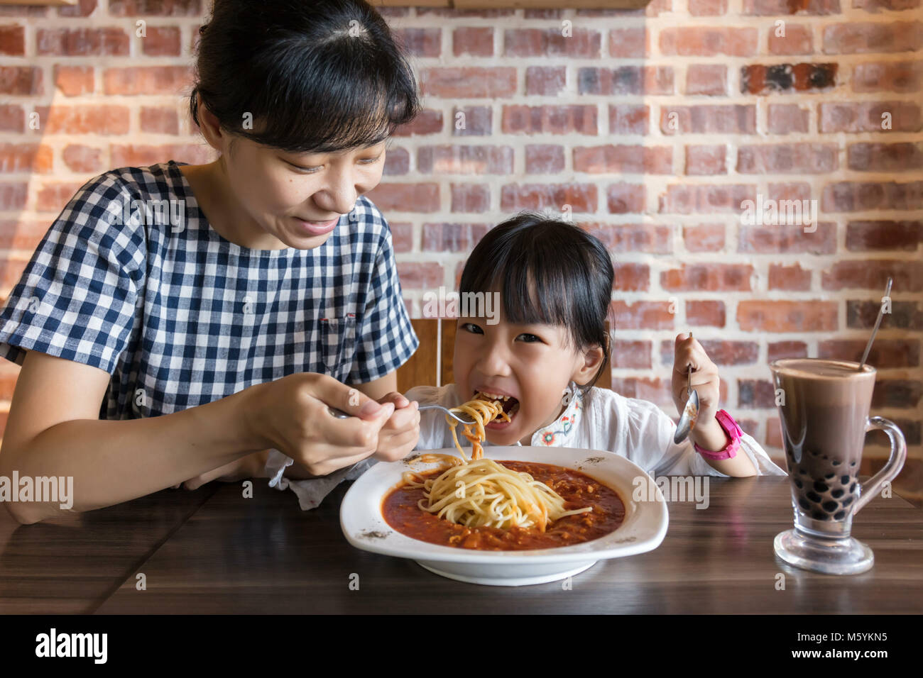 Asiatische chinesische Mutter und Tochter essen spaghetti bolognese im Restaurant Stockfoto
