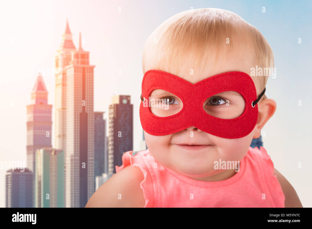 Cute Baby tragen rote Maske Vor modernes Gebäude Stockfoto