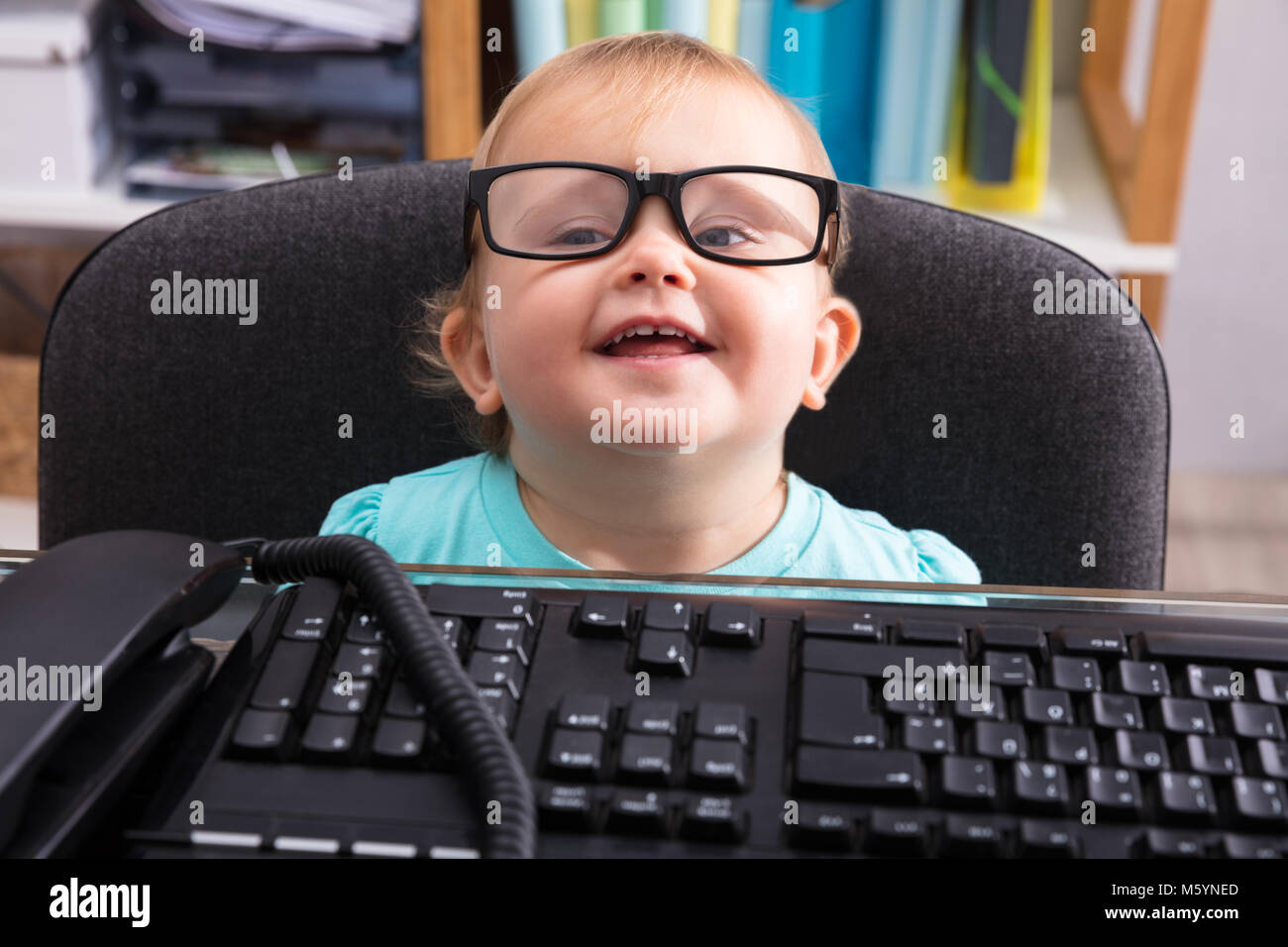 Computer Tastatur vor Süße kleine lächelnde Baby Brillen tragen Stockfoto