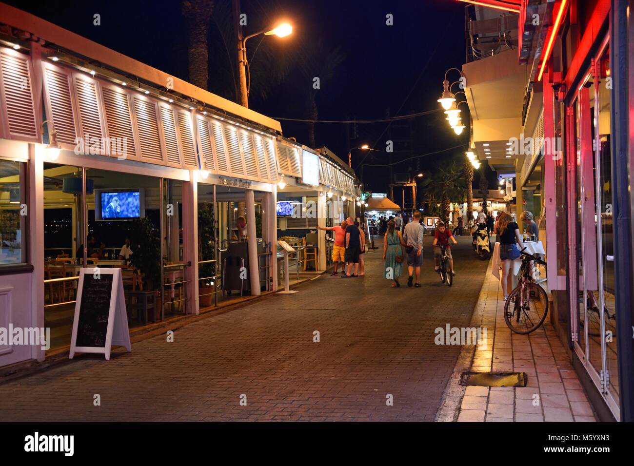 Waterfront Restaurants und Bars entlang der Hafen Shopping Straße bei Nacht, Hersonissos, Kreta, Griechenland, Europa. Stockfoto