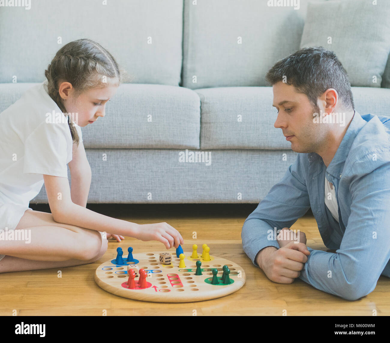 Kleine Mädchen und ihr Vater spielen Ludo. Stockfoto