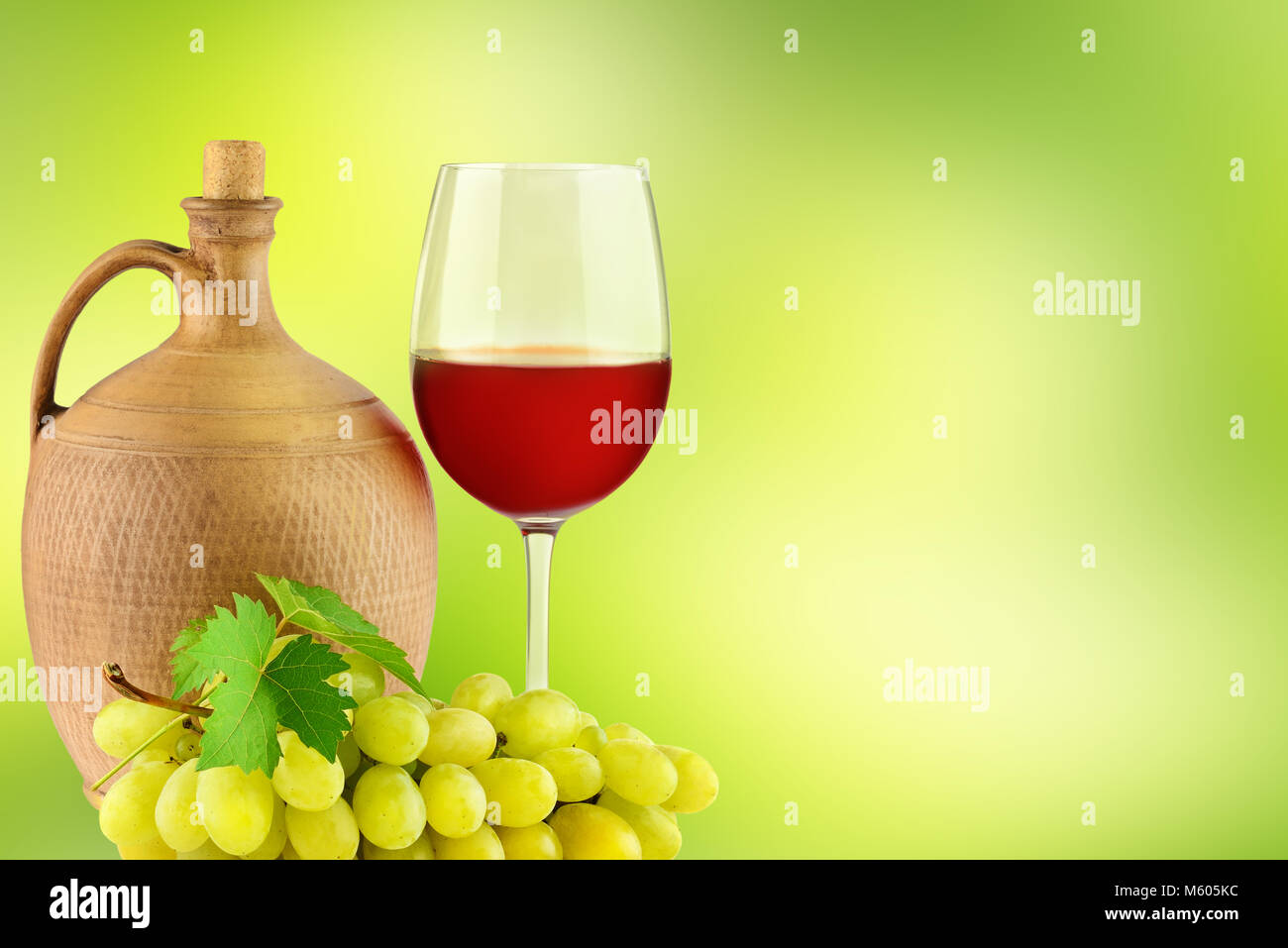 Krug mit Wein, Glas und Bündel Weintrauben auf grünem Hintergrund verschwommen Stockfoto